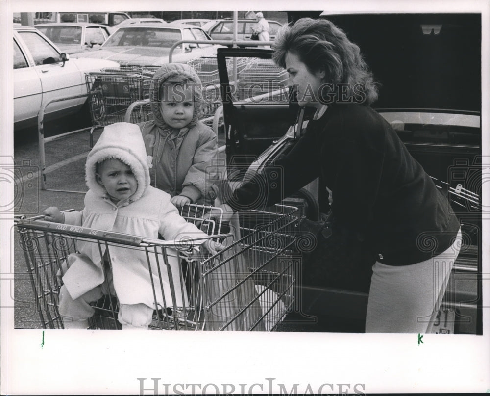 1988, Kelly Wells and children in grocery cart loads groceries in car - Historic Images