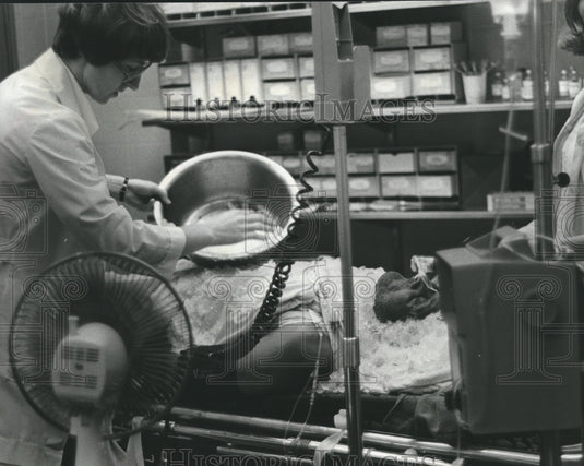 1980, Woman puts ice on man - abna17663 - Historic Images