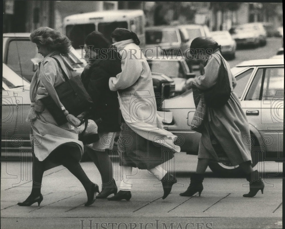 1986 women crossing street through windy weather, Alabama - Historic Images