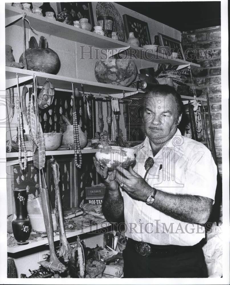 1978 Press Photo Hutto holds a pot, among shelves of artifacts. - abna18292 - Historic Images