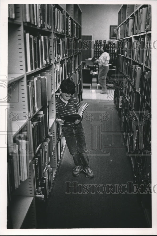 1987, Jason Whitcomb reading book at Bessemer Public Library, Alabama - Historic Images