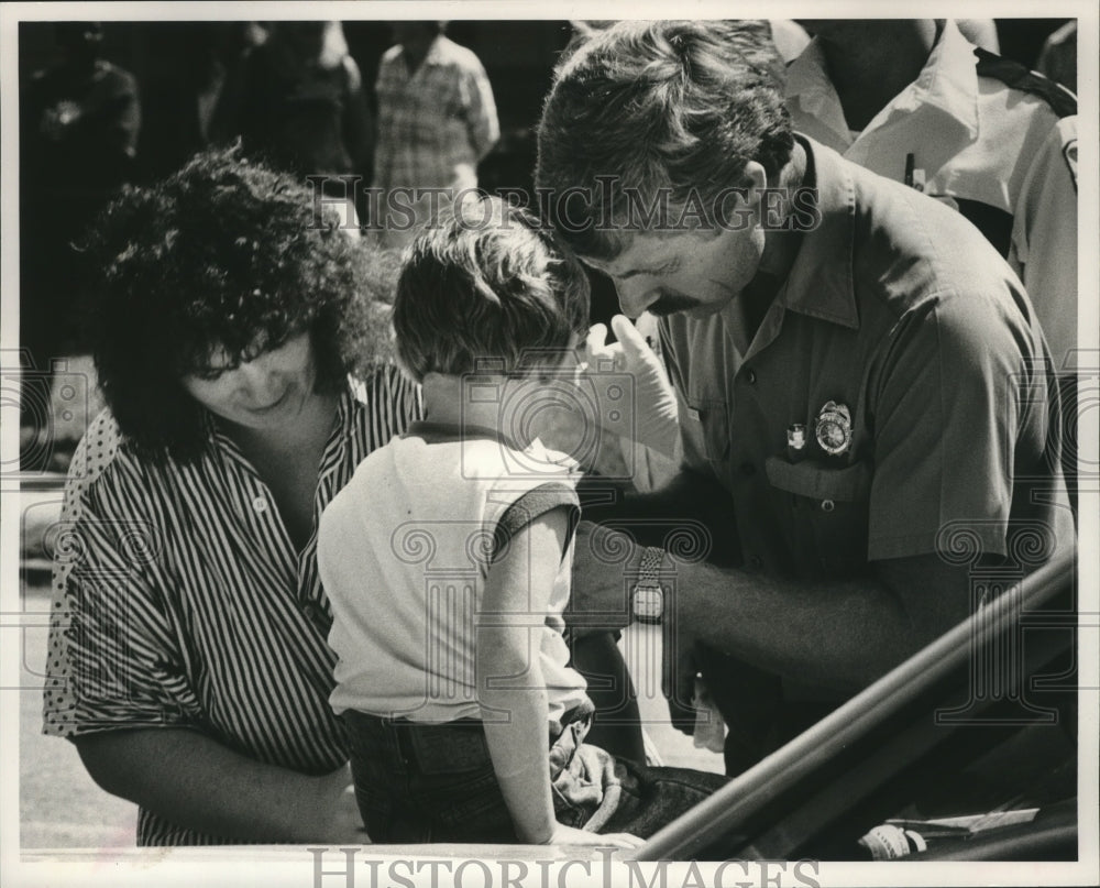 1989 Alabama-Birmingham Paramedic helps slightly burned child. - Historic Images