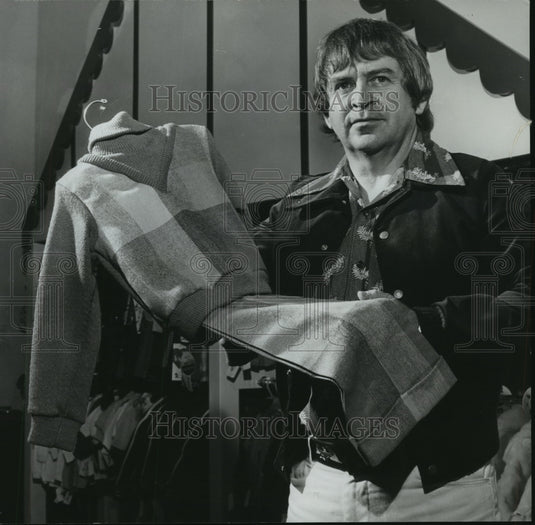 1973 Kiddie Shoppe manager Buddy Butler holds clothing for boy - Historic Images