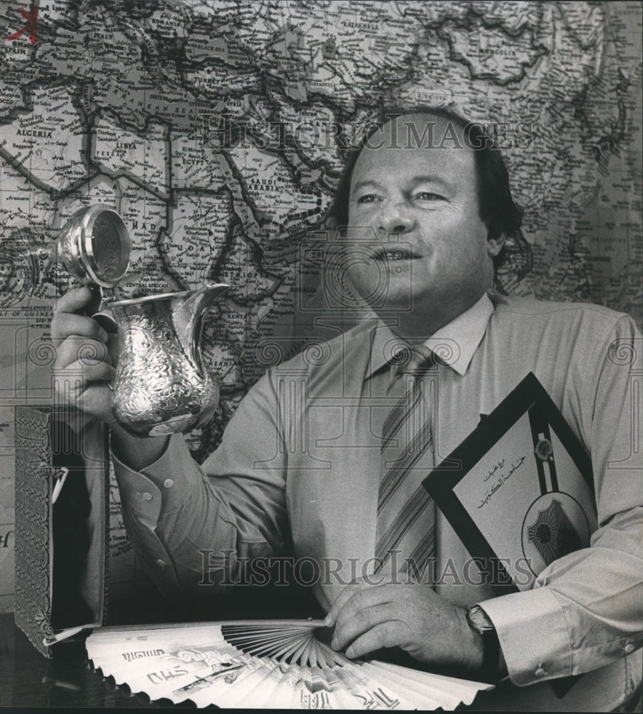 1985, Dr. Keith Blayney holds souvenirs in front of Saudi Arabia Map - Historic Images