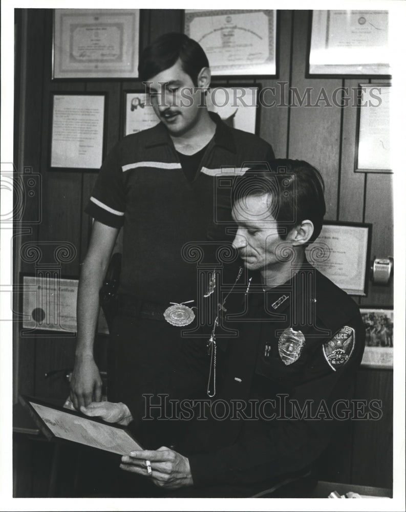 1984 Tom Burtnett and Tim Bledsoe, Policeman look over commendation - Historic Images