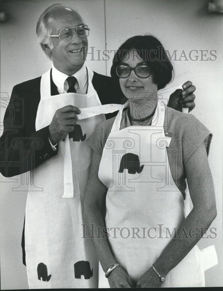 1980, Politician Jack Edwards helps Suzie Harris tie Republican apron - Historic Images