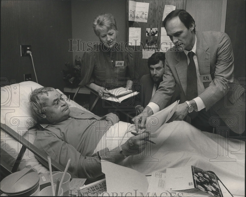 1985 Press Photo Hospitalized Chriss Doss Working with Associates from Bed - Historic Images