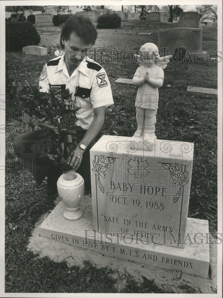 1989, Rick Harris, an EMT, places roses at Baby Hope Memorial - Historic Images