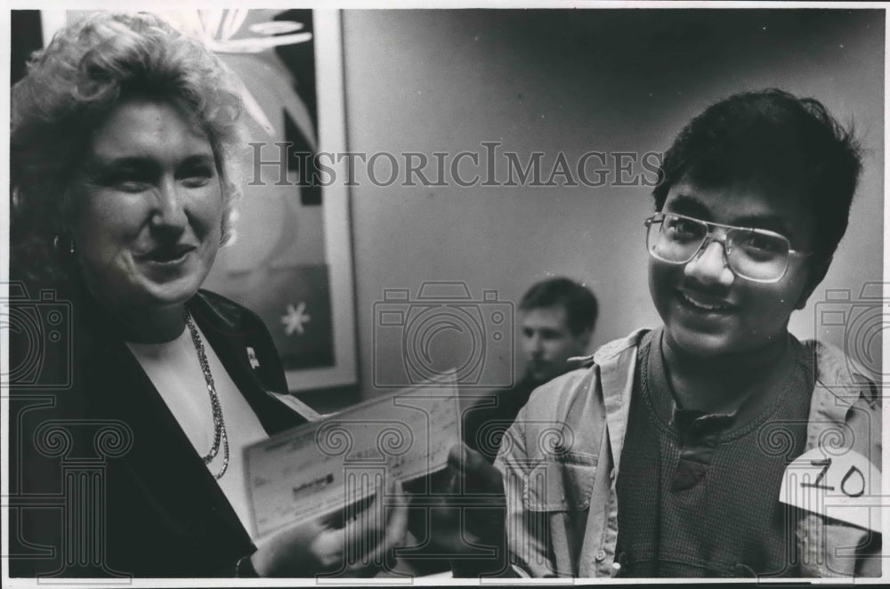 1989, Matt Joseph receives $100 check from Priscilla Holland, Alabama - Historic Images