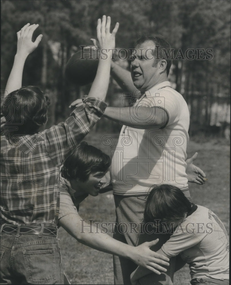 1976 James P. Lester, Insurance Broker playing football with kids - Historic Images