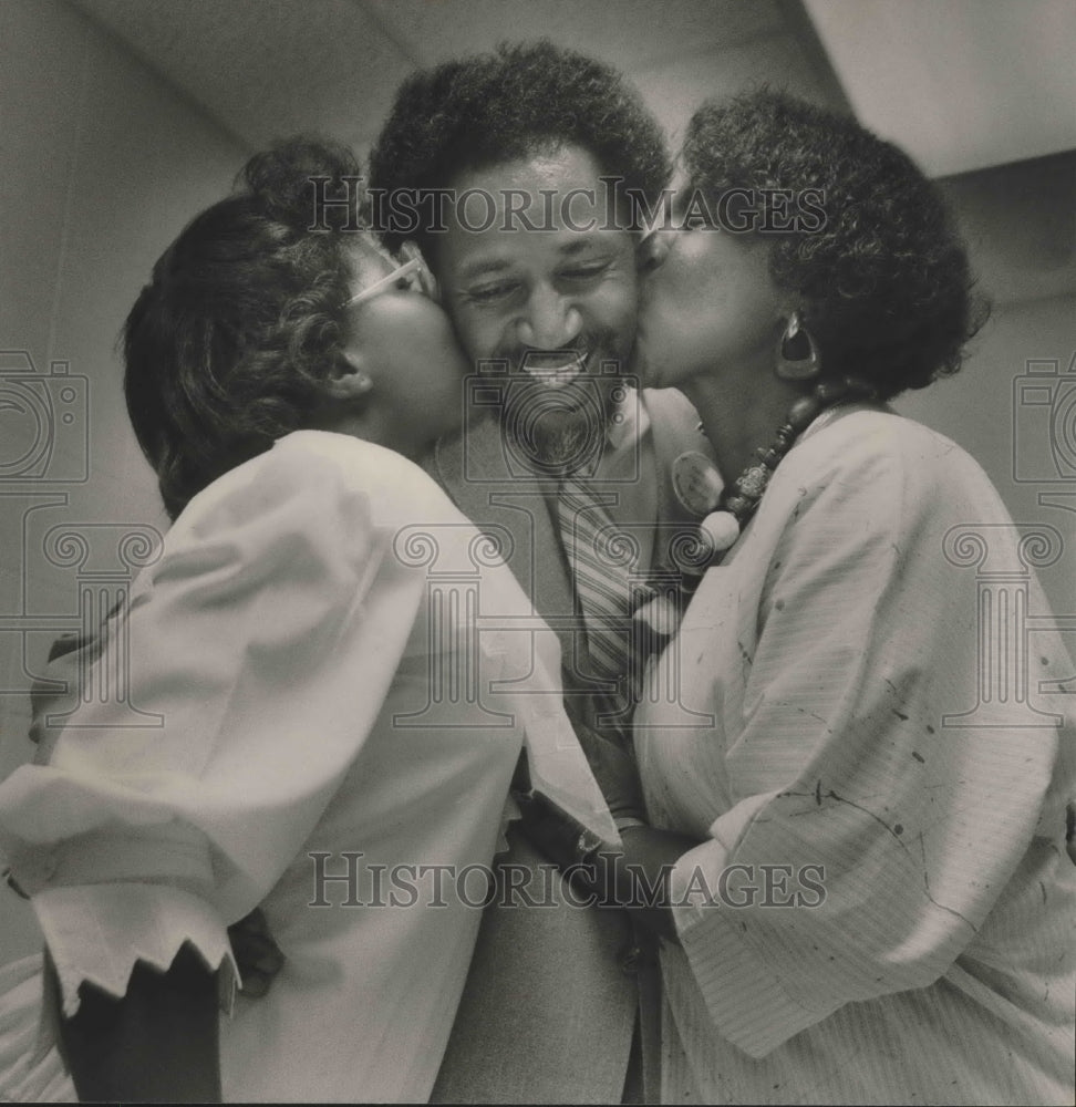 1986, Quitman Mitchell gets kiss from wife and daughter - abna36392 - Historic Images