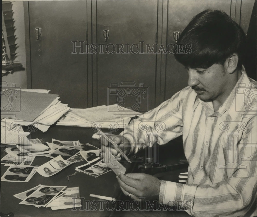 1973, Birmingham Policeman Douglas McBee with mug shot photographs - Historic Images