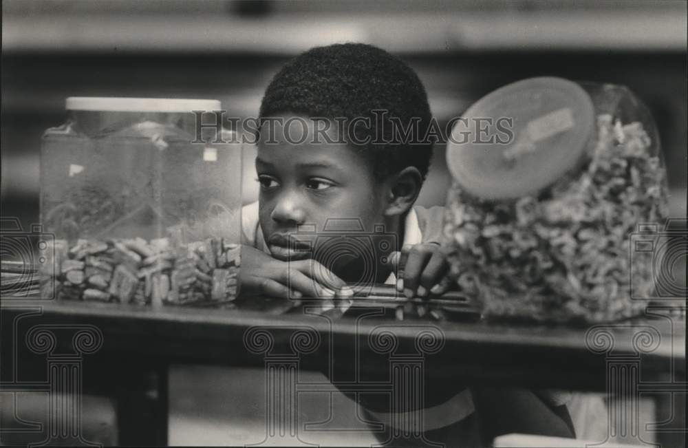 1988 Press Photo John Woolen looking at jars of candy, Birmingham, Alabama - Historic Images