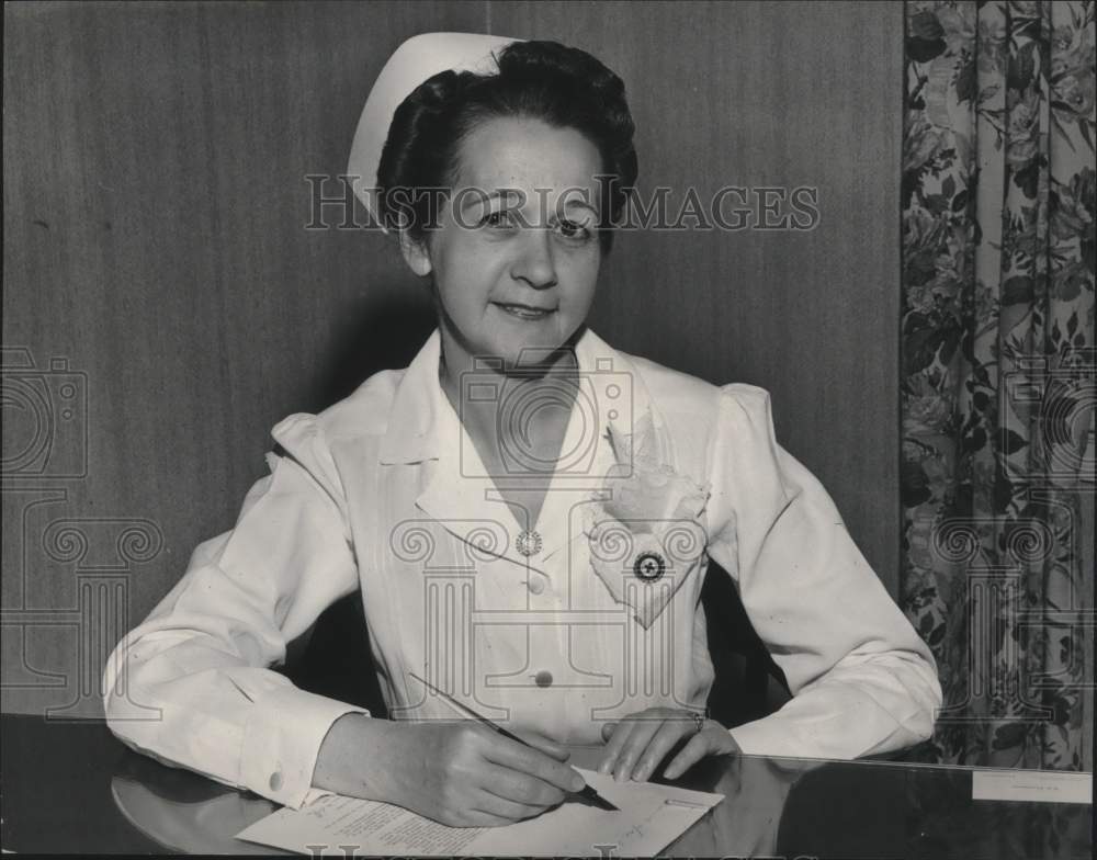 1950, Mrs. Ida V. Moffet in nursing uniform signing paper - abna37801 - Historic Images