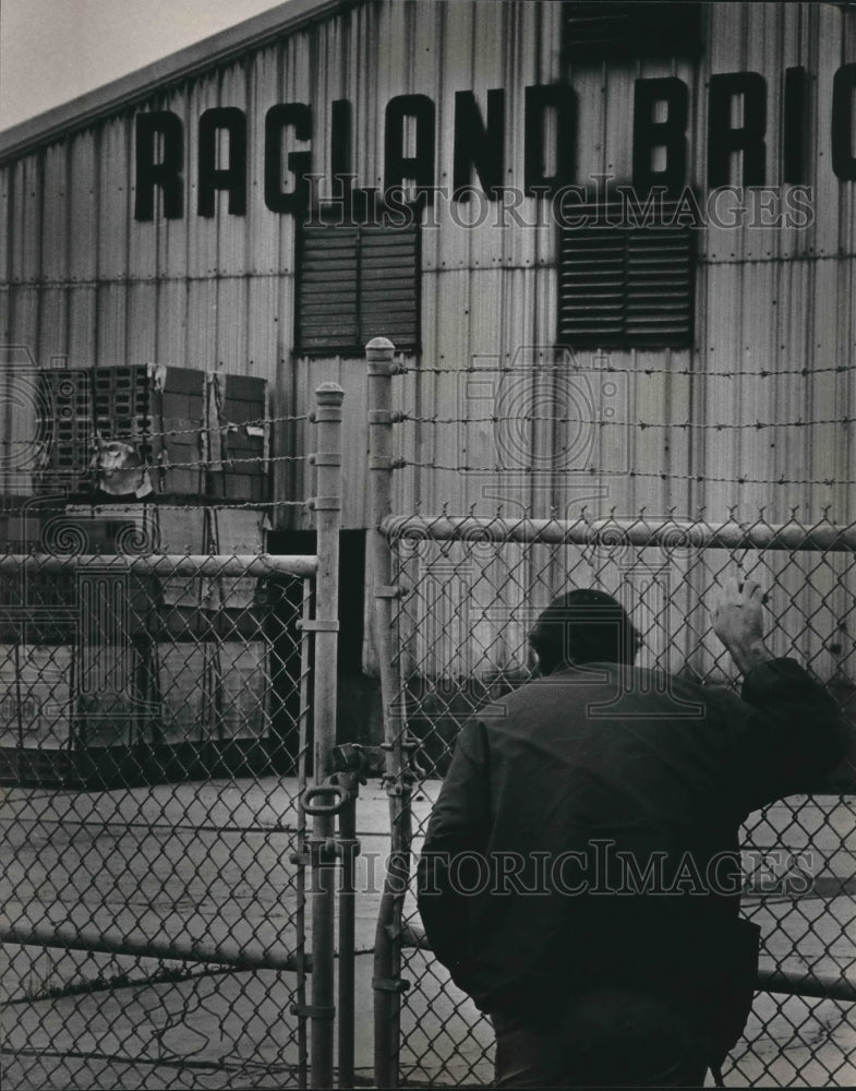 1983 Unidentified man outside locked gates at Ragland Brick Plant - Historic Images