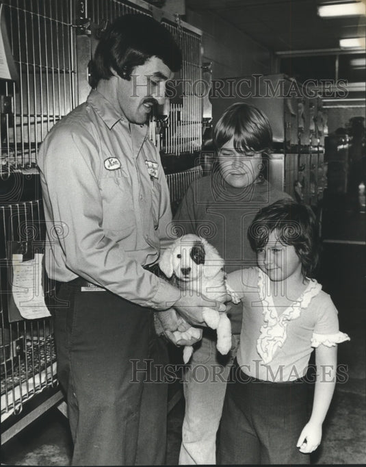 1975, Humane Society's Ron Kinglsey helps family select puppy - Historic Images