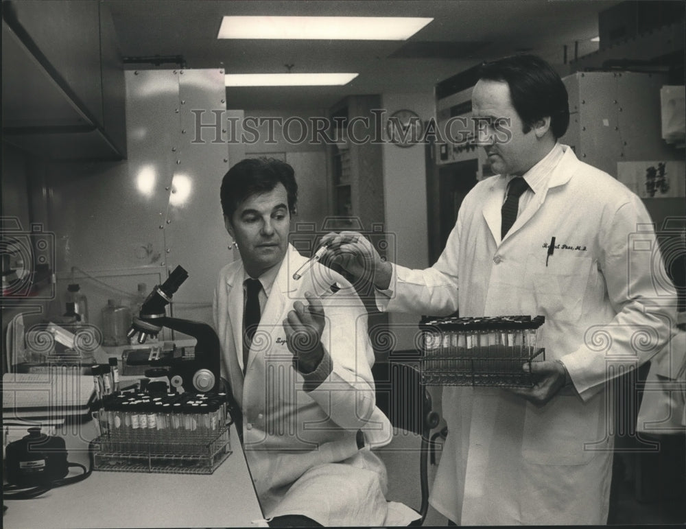 1985, Doctor Sergio Stagno and Doctor Bob Pass look at samples in lab - Historic Images