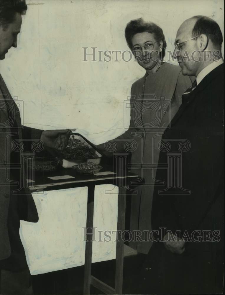 Press Photo Two Men and Woman Stand Around Table - abna45430 - Historic Images