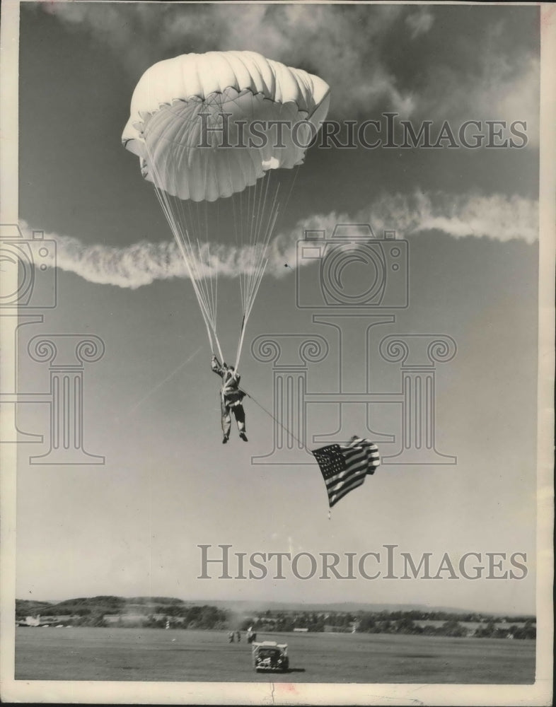 1950, Parachute jumper Jack Huber in air with flag in Birmingham - Historic Images