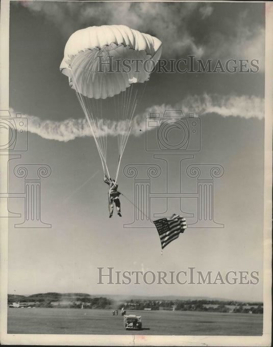 1950, Parachute jumper Jack Huber in air with flag in Birmingham - Historic Images