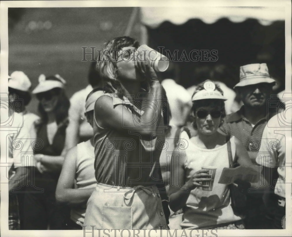 1974 Woman drinking from cup at golf tournament with spectators - Historic Images