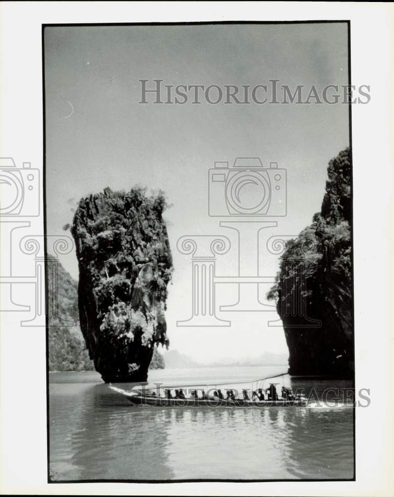 1986 Press Photo Boat full of people motors past two huge rocks in Thailand- Historic Images