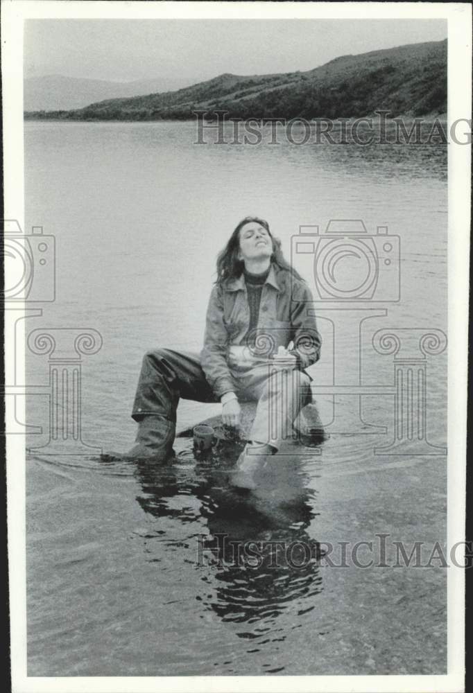 Press Photo Person sitting on a rock in a lake - afa47782- Historic Images