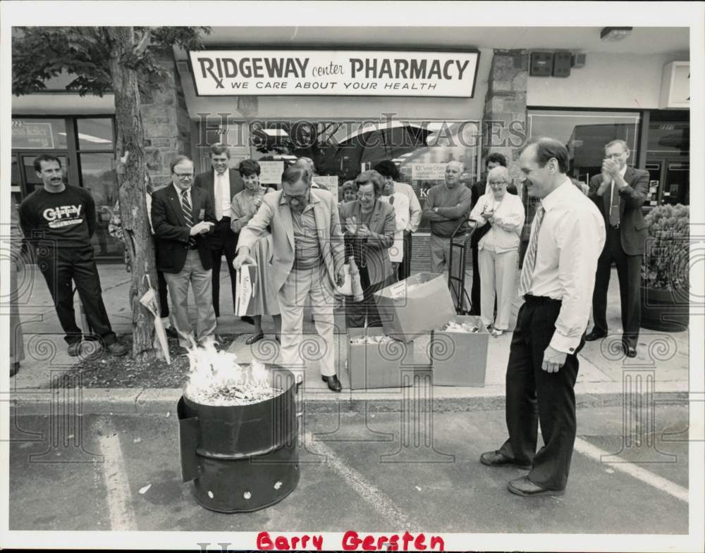 1987 Press Photo John Candelmo burns Carton of Cigarettes outside Pharmacy- Historic Images