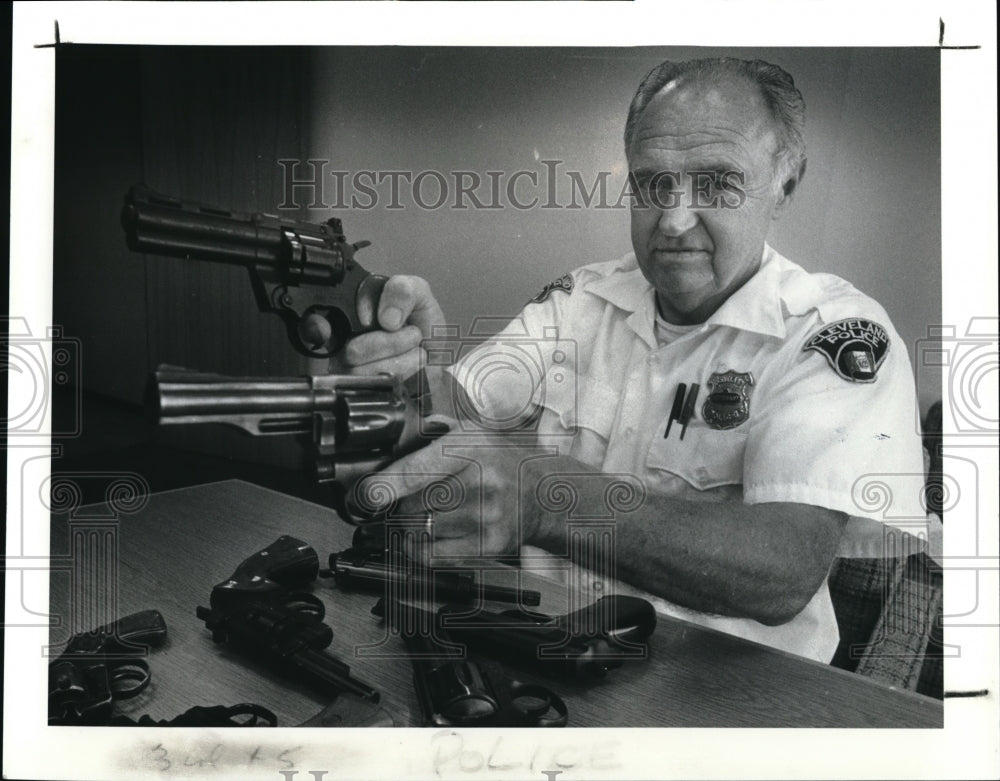 1987 Press Photo Lt. Walter Galyin holds up a 357 Mg. and a pellet gun - Historic Images