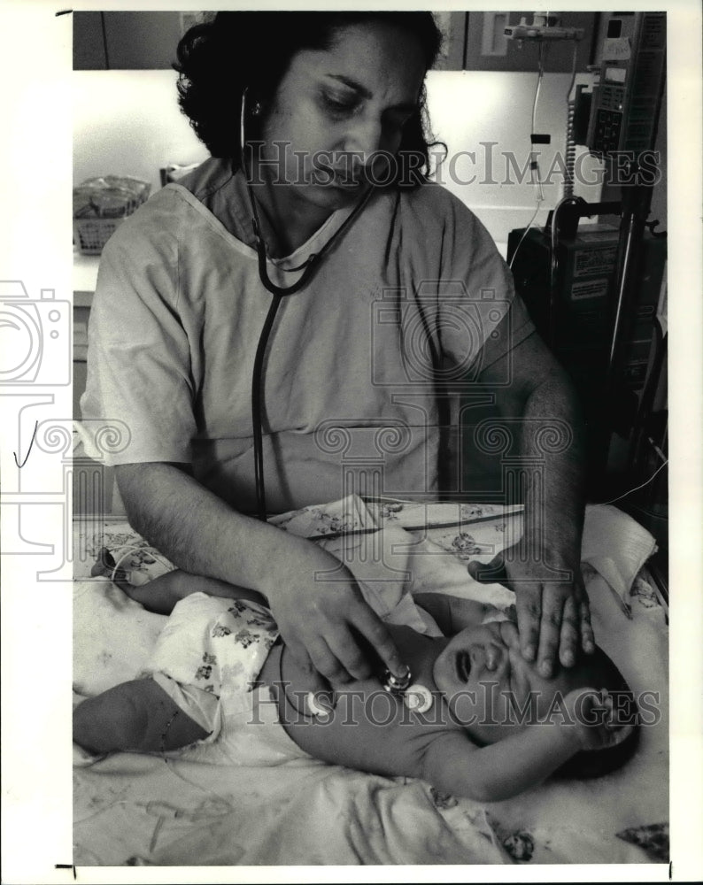 1991, Dr. Prem Mehandru checks baby&#39;s condition at Rainbow Hospital - Historic Images