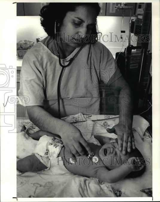 1991, Dr. Prem Mehandru checks baby's condition at Rainbow Hospital - Historic Images