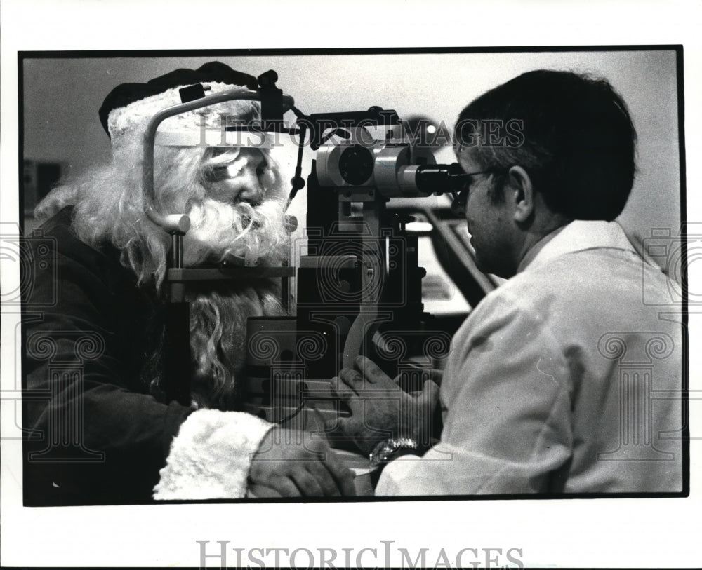 1985 Press Photo Chief of staff Dr. Carl Asseff examines Santa's eyes - Historic Images