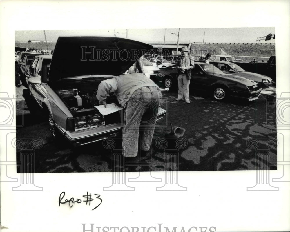 1991 Press Photo Bidders look under the hood of the cars at auction lot - Historic Images