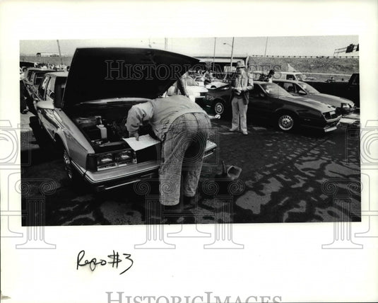 1991 Press Photo Bidders look under the hood of the cars at auction lot - Historic Images