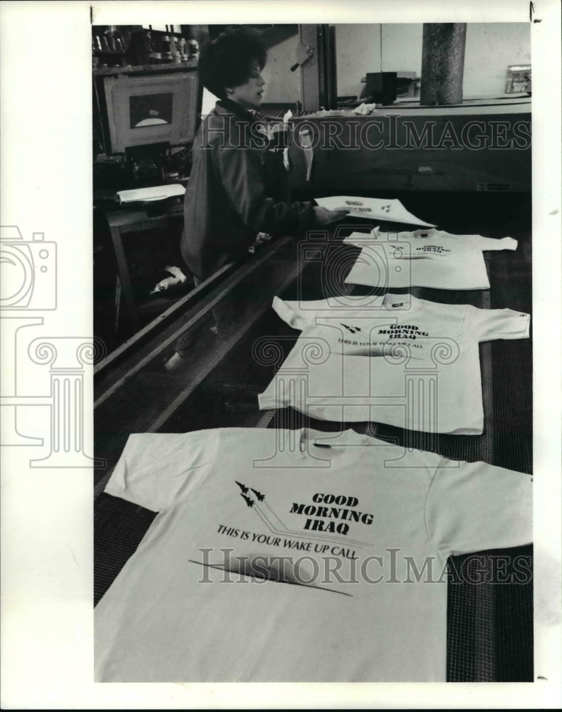 1991 Press Photo Bobbi Skiles works on the latest Daffy Dan shirt w/ war theme - Historic Images