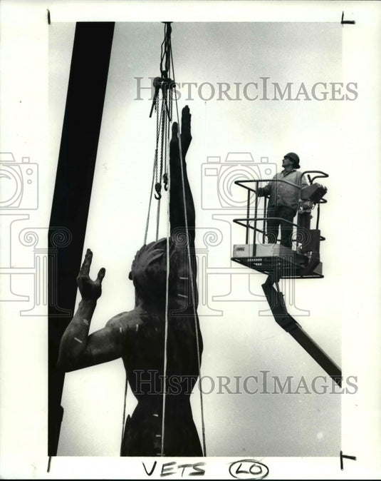 1989 Press Photo Workman inspects the rigging on the Peace Statue on Mall C - Historic Images