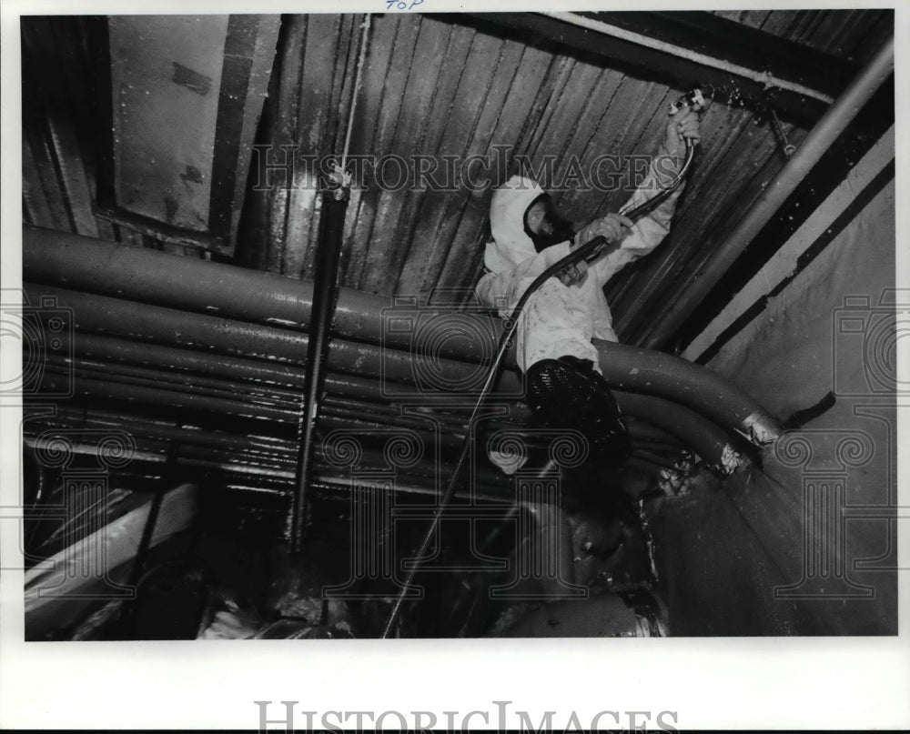 1990 Press Photo Worker Brian Sullivan uses a hose to wash asbestos off the - Historic Images