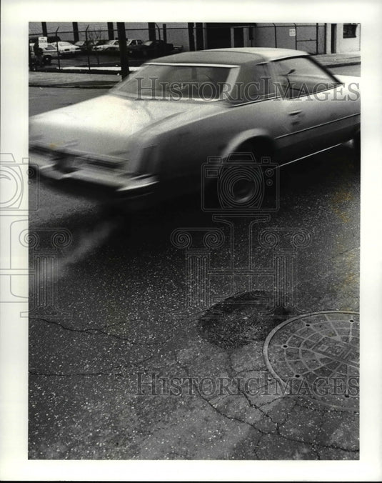 1987 Press Photo Car avoid chuckholes as it races eastbound on St. Clair-Historic Images