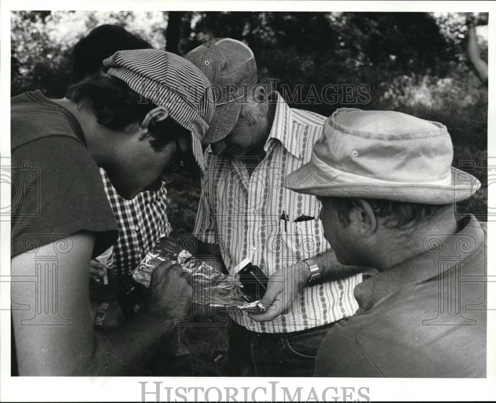 Press Photo Men are Looking at the Object in a Piece of Foil - Historic Images