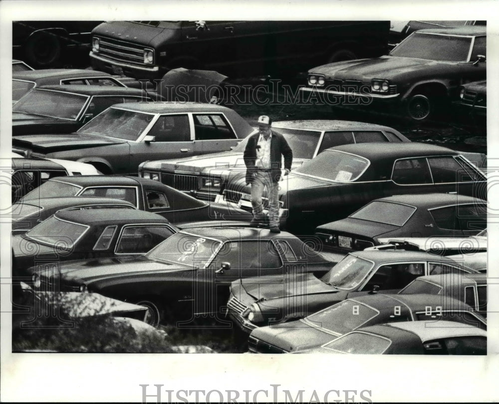 1986 Press Photo The man atop the parked cars at the impound lot - Historic Images