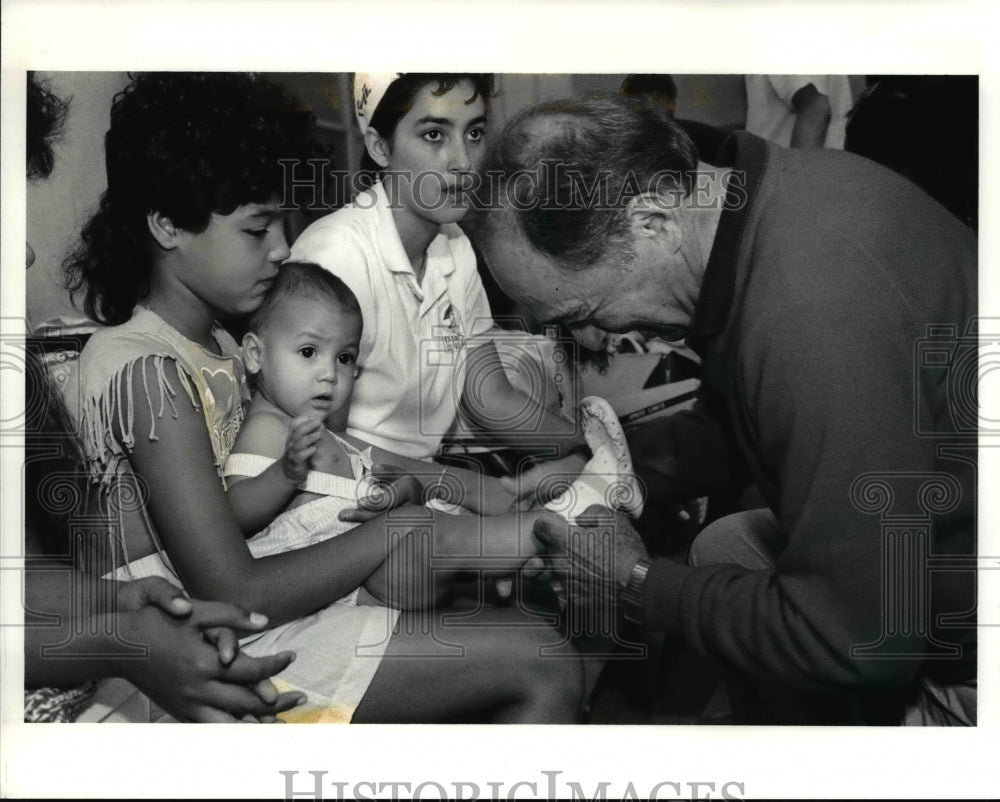 1990 Press Photo Morrie Sayee tries a pair of slippers to Maelyn - cva80351-Historic Images