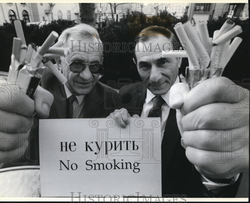 1989 Press Photo Dr. Lupukhin joins Dr. Miller grasps fistfuls of cigarettes - Historic Images