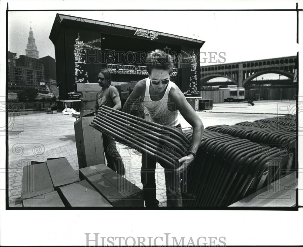 1987 Press Photo Mark D&#39;Shea stacks chairs after they were taken out of box in - Historic Images