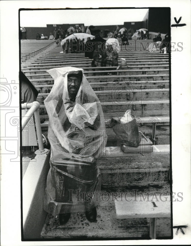 1982 Press Photo William Brown sits in rain soaked bleachers at stadium - Historic Images