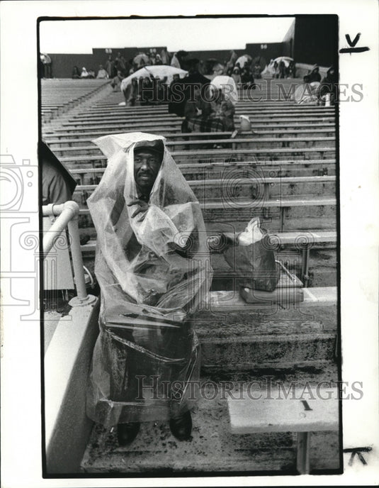 1982 Press Photo William Brown sits in rain soaked bleachers at stadium - Historic Images