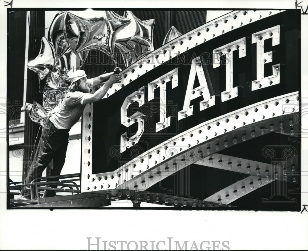 1984 Press Photo Worker for Buddy Simon Sign ties silver ball of State Theater - Historic Images