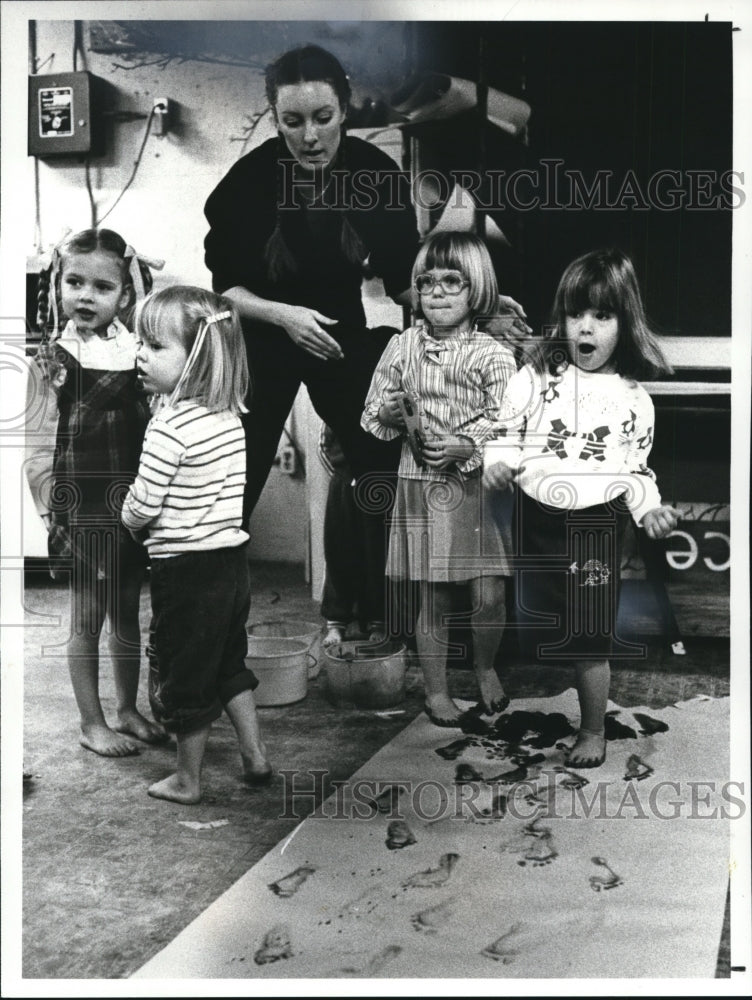 1982 Press Photo Teacher Deborah Naiman, assists children to do foot paintings. - Historic Images