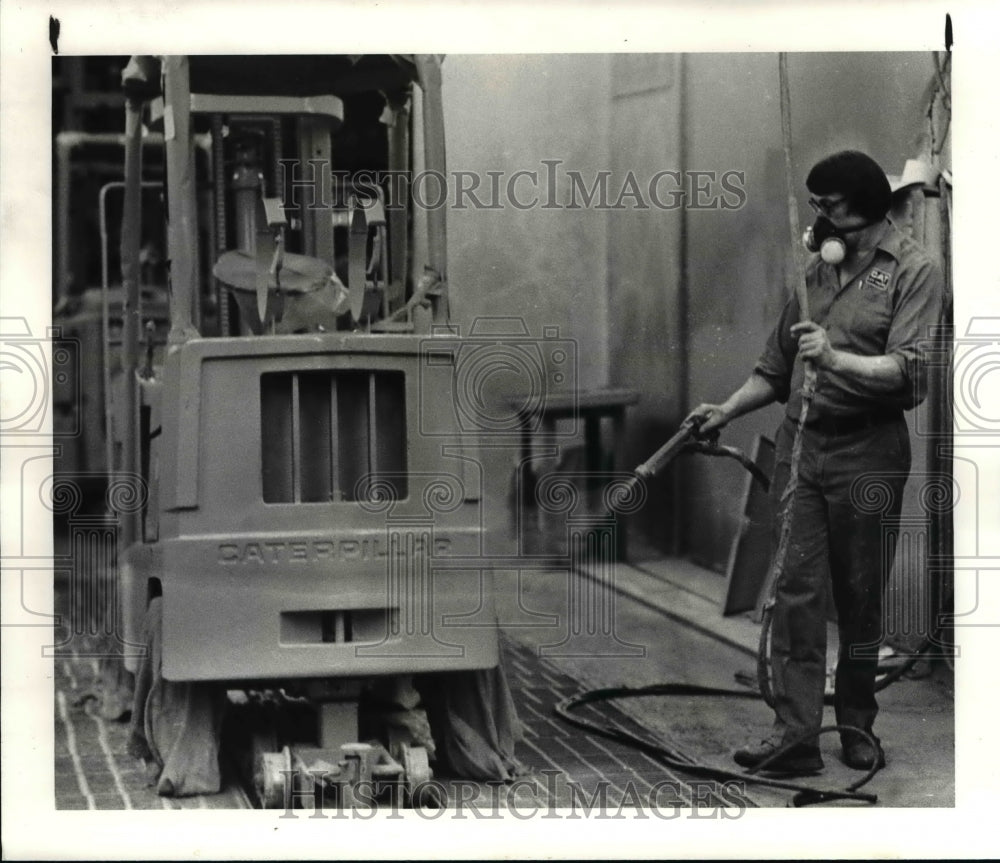 1983 Press Photo Joe Prozovic spray paints a Towmotor unit in Mentor Ohio plant - Historic Images