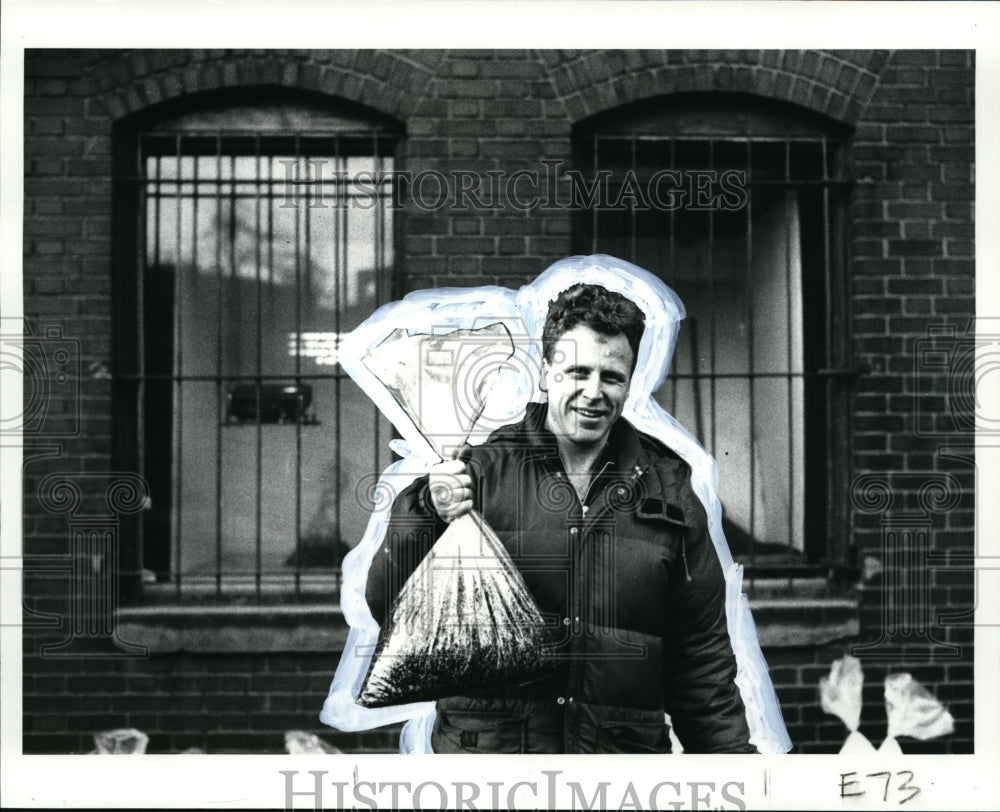 1987 Press Photo Artist Ray Langenbach passes out bags of asphalt - cvb12838 - Historic Images