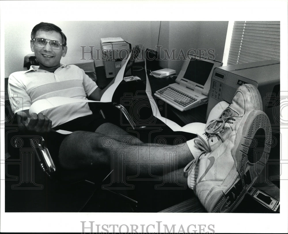 1991 Press Photo Thomas Thatcher President of Tharo Systems lounging at his desk - Historic Images